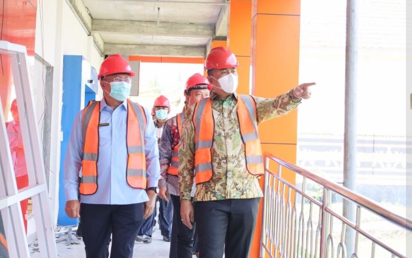 Bupati OKU Selatan bersama jajaran meninjau pembangunan gedung rumah sakit dengan mengenakan helm proyek dan rompi keselamatan.