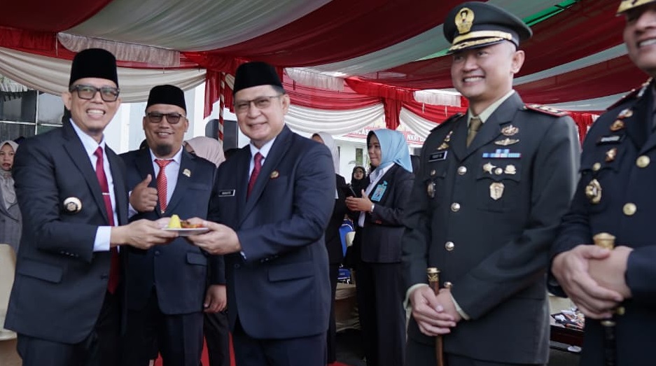 Bupati OKU H Teddy Meilwansyah dan Wabup H Marjito Bachri memegang potongan tumpeng di momen hardiknas.