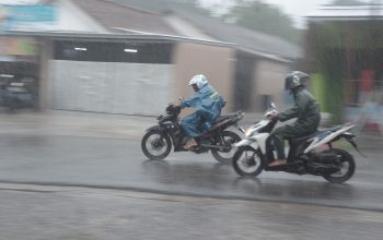 Pengendara sepeda motor memacu kencang tunggangannya di bawah guyuran hujan. BPBD OKU mengingatkan masyarakat potensi hujan 3 hari kedepan. foto : Mustofa / okusatu.id