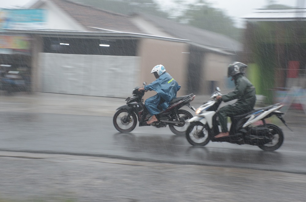 Pengendara sepeda motor memacu kencang tunggangannya di bawah guyuran hujan. BPBD OKU mengingatkan masyarakat potensi hujan 3 hari kedepan. foto : Mustofa / okusatu.id